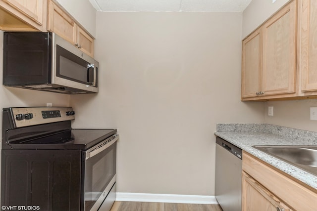 kitchen featuring light brown cabinets, appliances with stainless steel finishes, and light hardwood / wood-style flooring