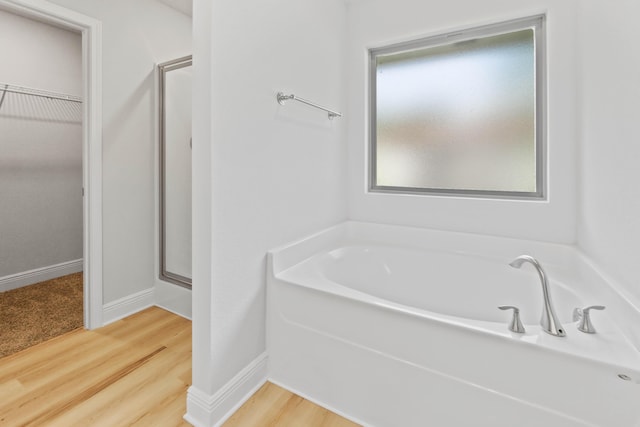 5816 Crestlake Dr, Crestview, FL 32536 - full bath with a bath, a walk in closet, a shower stall, wood finished floors, and baseboards
