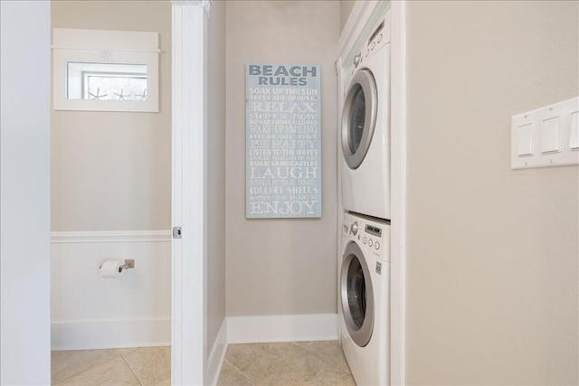 clothes washing area with light tile floors and stacked washing maching and dryer