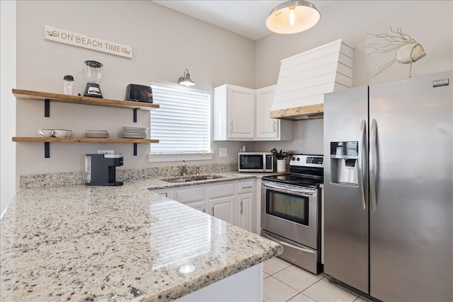 kitchen with appliances with stainless steel finishes, light stone counters, white cabinets, sink, and light tile floors