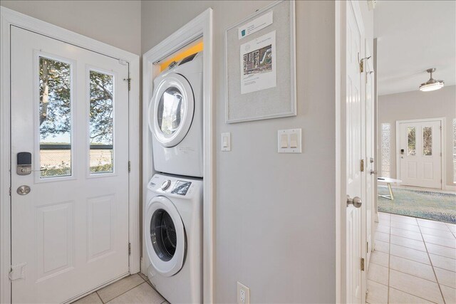 laundry area featuring stacked washer / dryer and light tile floors