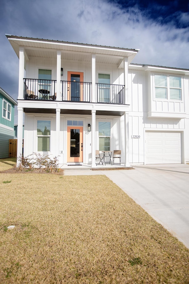 view of front of property featuring a front lawn, a garage, and a balcony