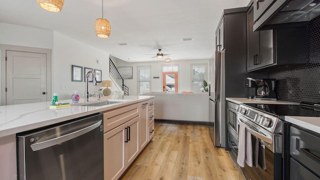 kitchen featuring decorative light fixtures, appliances with stainless steel finishes, light hardwood / wood-style flooring, ceiling fan, and sink