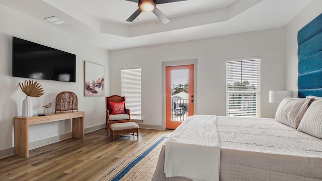 bedroom featuring hardwood / wood-style flooring, ceiling fan, a raised ceiling, and access to outside