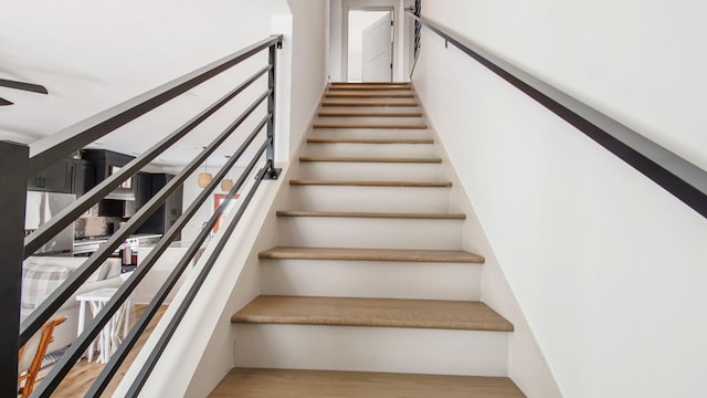 stairway with ceiling fan and light hardwood / wood-style floors