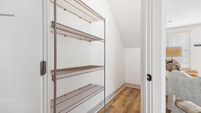 spacious closet featuring light hardwood / wood-style flooring and vaulted ceiling