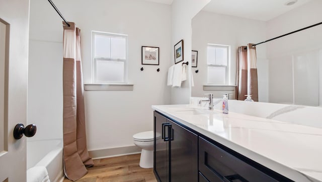 full bathroom with shower / tub combo with curtain, toilet, wood-type flooring, vanity, and a wealth of natural light