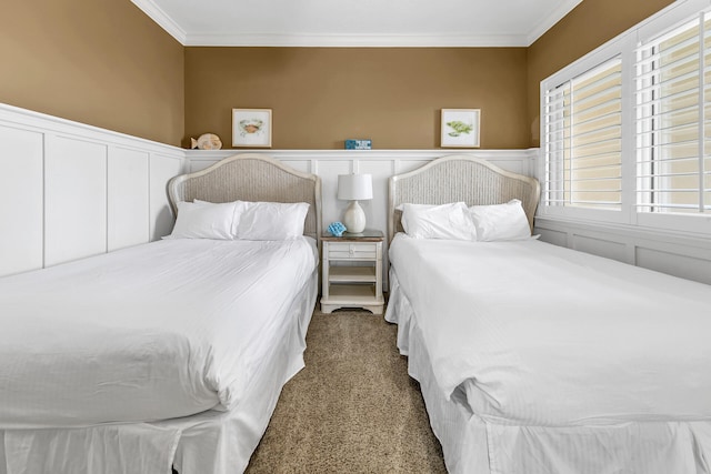 carpeted bedroom with ornamental molding, wainscoting, and a decorative wall