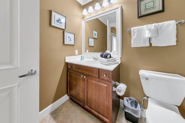 half bathroom with baseboards, vanity, toilet, and tile patterned floors