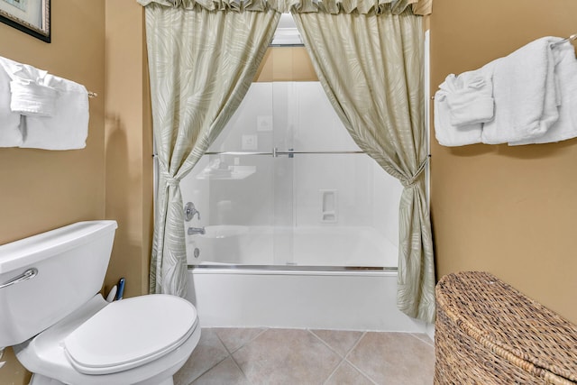 bathroom featuring tile patterned flooring, combined bath / shower with glass door, and toilet