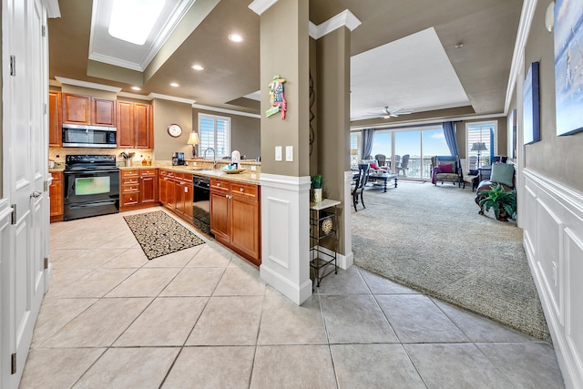 kitchen featuring light carpet, a sink, open floor plan, black appliances, and a tray ceiling