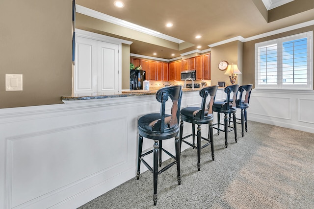 kitchen featuring stainless steel microwave, a kitchen breakfast bar, freestanding refrigerator, a peninsula, and a decorative wall