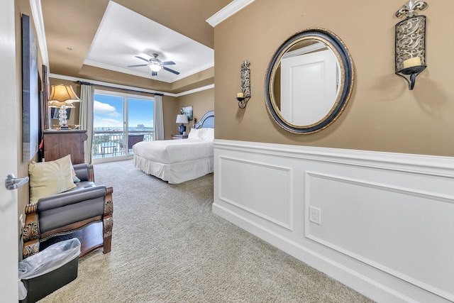 carpeted bedroom with crown molding, a decorative wall, wainscoting, and access to exterior