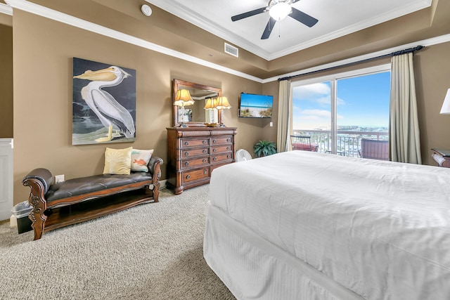 bedroom with carpet floors, visible vents, a tray ceiling, and ornamental molding