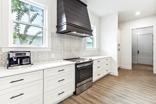 kitchen with light wood-type flooring, stainless steel electric range, white cabinetry, and custom range hood