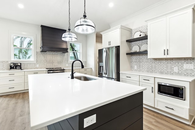 kitchen featuring custom range hood, a healthy amount of sunlight, stainless steel appliances, sink, and an island with sink