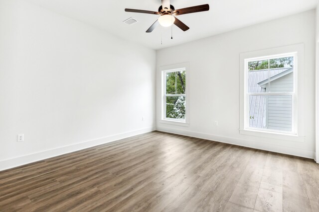 empty room featuring hardwood / wood-style flooring, a wealth of natural light, and ceiling fan