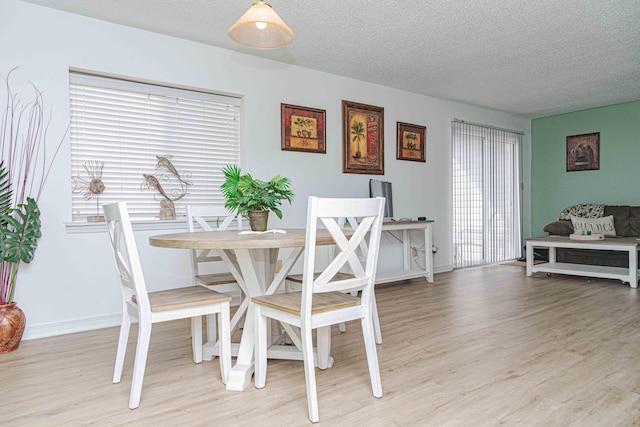 dining room featuring a textured ceiling and light hardwood / wood-style floors