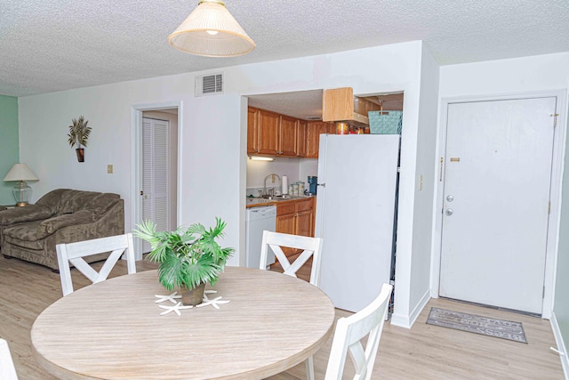 dining area featuring sink, light hardwood / wood-style floors, and a textured ceiling