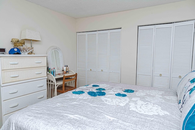 bedroom with a textured ceiling and multiple closets