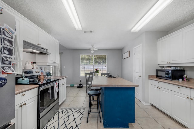 kitchen with stainless steel electric range oven, white cabinets, a breakfast bar, a center island, and light tile floors