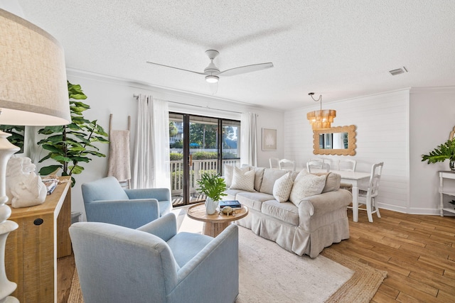 living room featuring ceiling fan with notable chandelier, hardwood / wood-style flooring, a textured ceiling, and crown molding