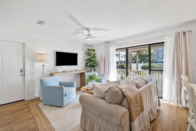 living room with ceiling fan, light hardwood / wood-style flooring, crown molding, and a textured ceiling