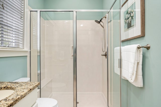 bathroom with vanity, toilet, and a shower with door