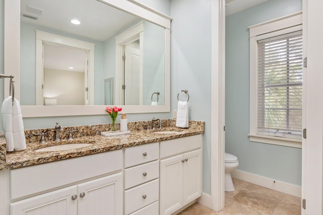 bathroom with tile flooring, toilet, vanity with extensive cabinet space, and dual sinks