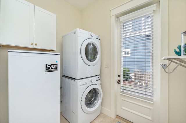 washroom featuring cabinets, stacked washer and dryer, and light tile floors