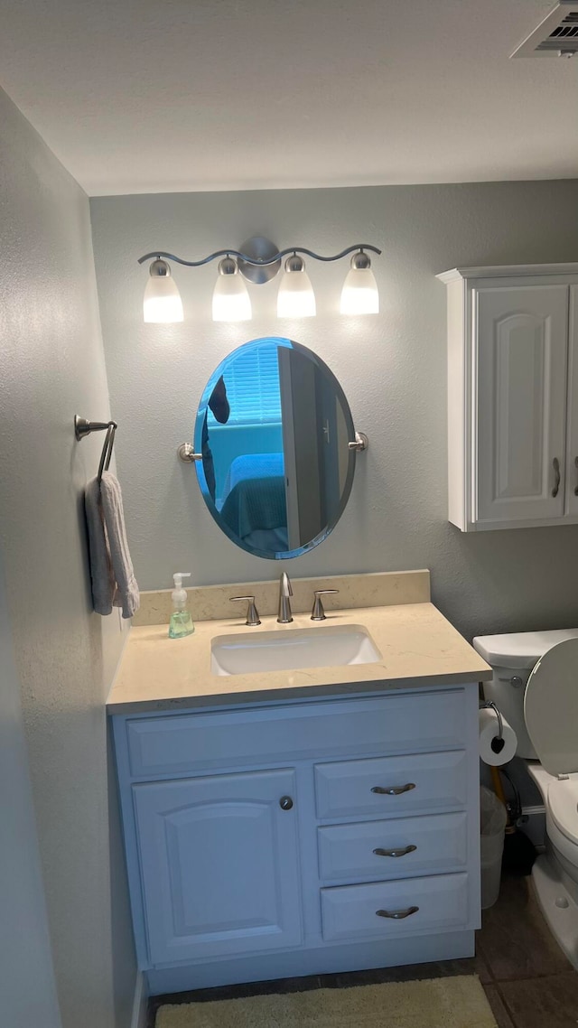 bathroom featuring tile floors, vanity, and toilet