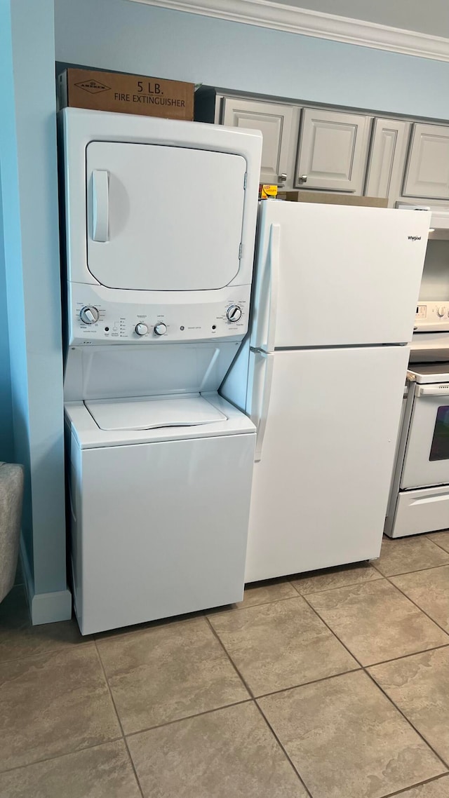 laundry area featuring stacked washer and clothes dryer, crown molding, and light tile flooring