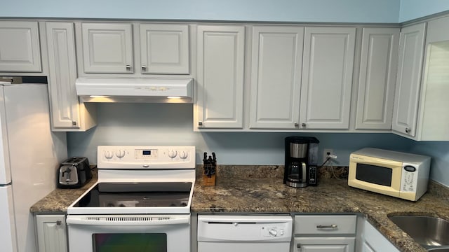 kitchen featuring dark stone countertops, white appliances, and wall chimney range hood