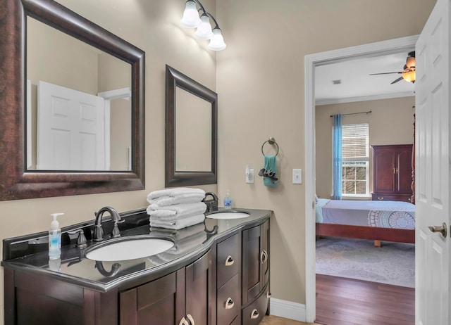 bathroom with double vanity, ceiling fan, crown molding, and wood-type flooring