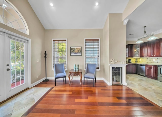 living area with wine cooler, ornamental molding, vaulted ceiling, a notable chandelier, and light tile floors