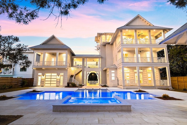 back house at dusk featuring a patio, a balcony, and pool water feature