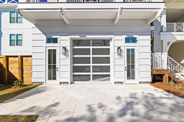 property entrance featuring french doors, a balcony, and a patio