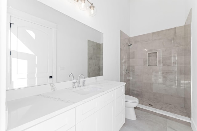 bathroom with vanity, tile floors, toilet, and a tile shower