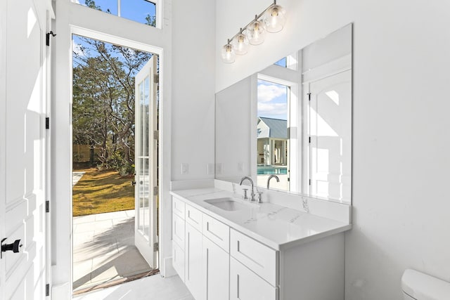 bathroom with a healthy amount of sunlight, oversized vanity, and toilet