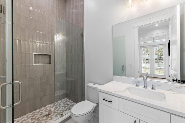 bathroom with a shower with door, vanity, and toilet