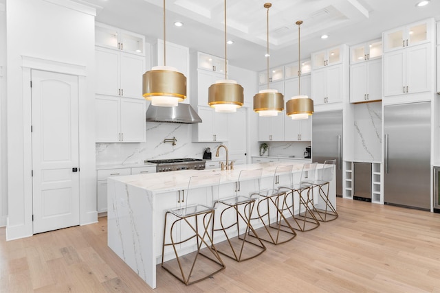 kitchen featuring tasteful backsplash, pendant lighting, a kitchen island with sink, and light wood-type flooring