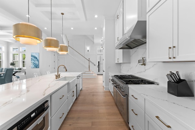 kitchen featuring backsplash, light hardwood / wood-style flooring, double oven range, hanging light fixtures, and white cabinetry