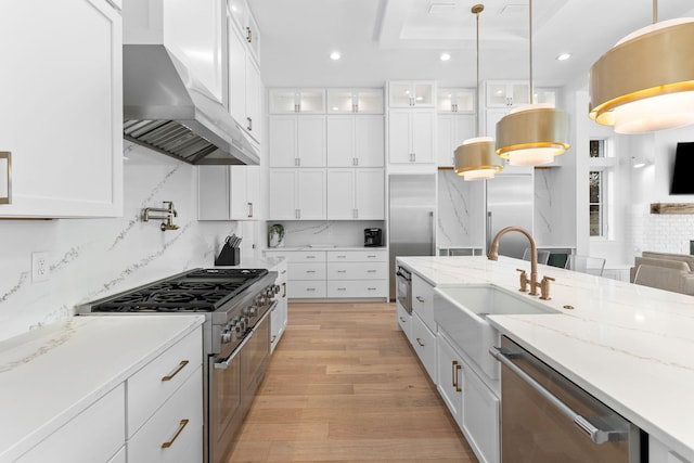 kitchen with appliances with stainless steel finishes, tasteful backsplash, light wood-type flooring, white cabinetry, and a tray ceiling