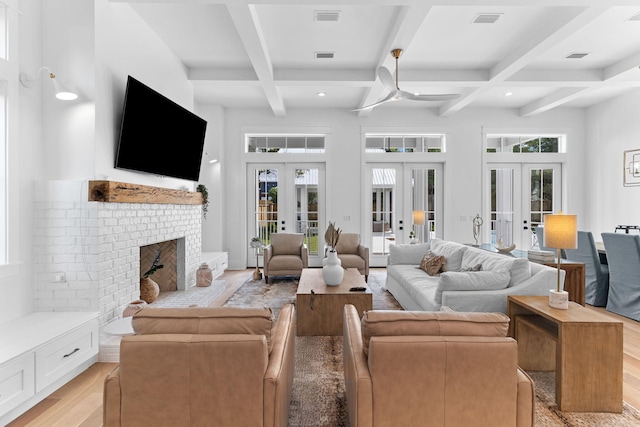 living room featuring french doors, coffered ceiling, a brick fireplace, and light wood-type flooring