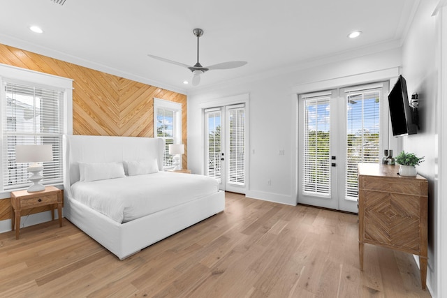 bedroom featuring light hardwood / wood-style floors, wood walls, crown molding, access to outside, and french doors