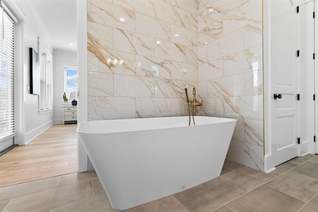 bathroom with tile walls, hardwood / wood-style floors, and a tub