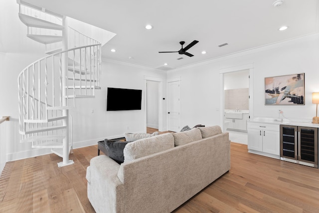 living room with ornamental molding, wine cooler, light hardwood / wood-style flooring, and ceiling fan