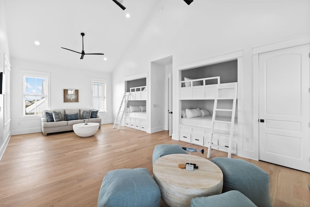 living room featuring high vaulted ceiling, ceiling fan, and light wood-type flooring