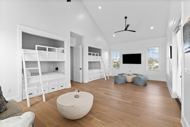 living room with high vaulted ceiling, ceiling fan, and light wood-type flooring