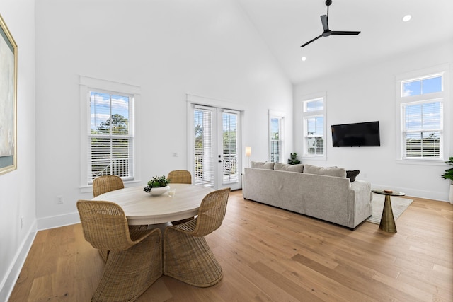 dining space with high vaulted ceiling, ceiling fan, light wood-type flooring, and french doors